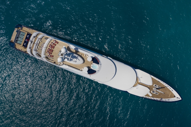 Bird's eye view of a running yacht in a calm, green ocean