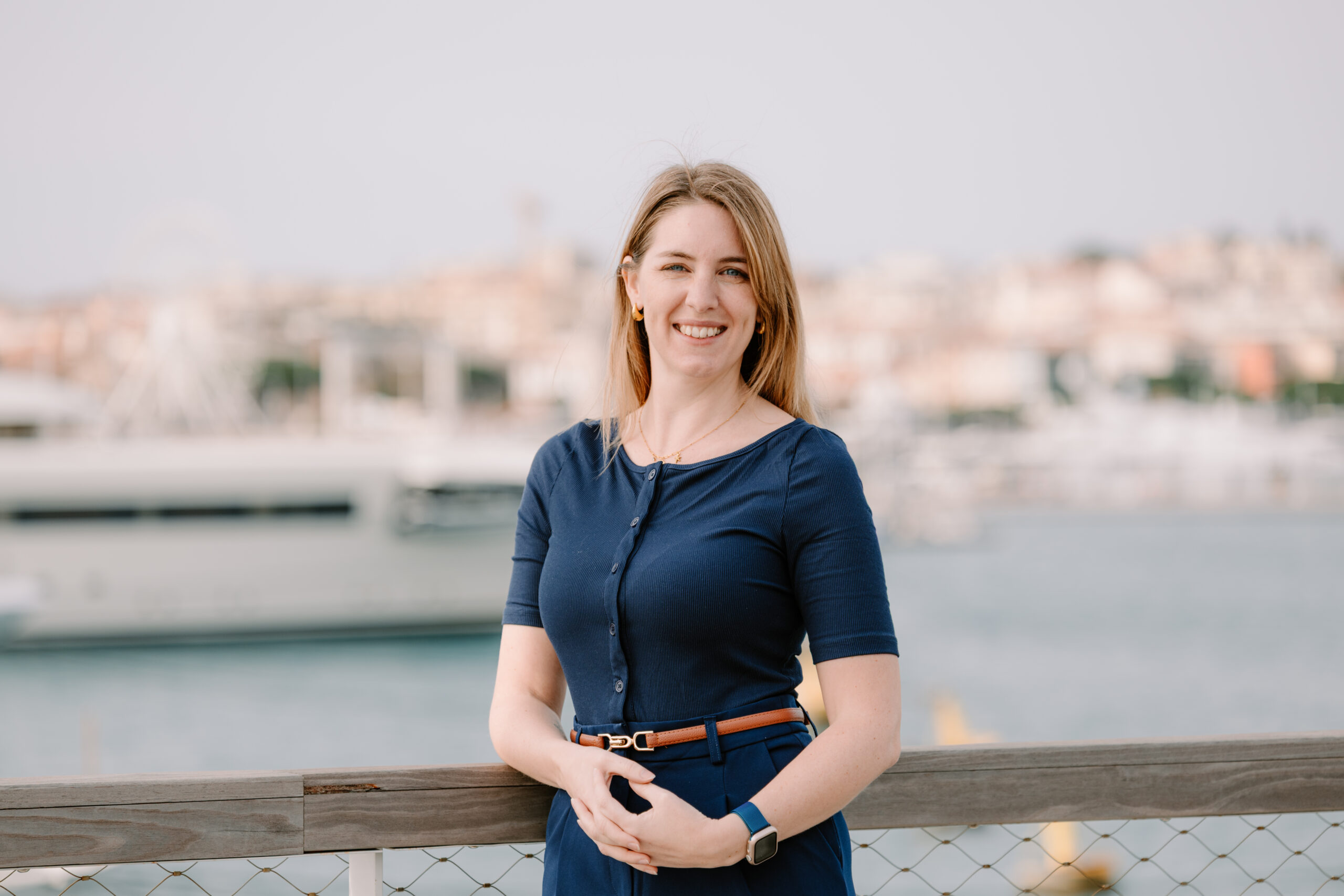 Kayleigh Liddell, Crew HR Manager at Hill Robinson, photographed outdoors in Antibes with a marina and coastal town in the background.